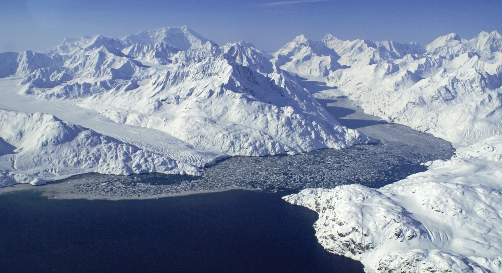 Snowy mountain range with ice melting into ocean